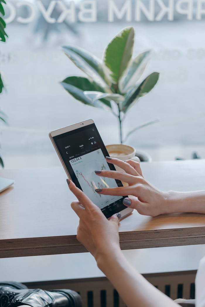 Person using a tablet to analyze stock market graphs, symbolizing remote work and finance.